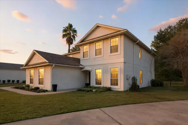 a view of a white house with a yard and plants