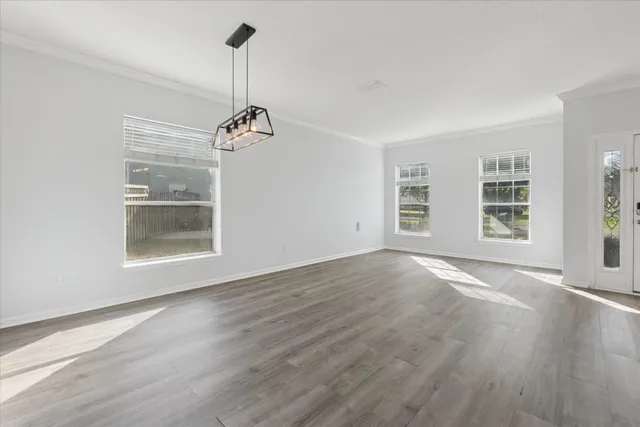 a view of an empty room with a window and wooden floor