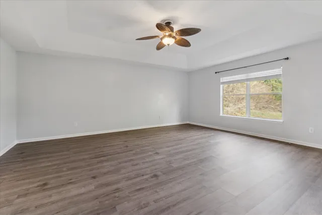 a view of an empty room with a window and wooden floor