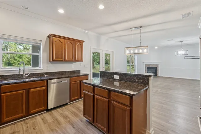 a kitchen with stainless steel appliances granite countertop wooden cabinets a sink a stove a dining table and chairs