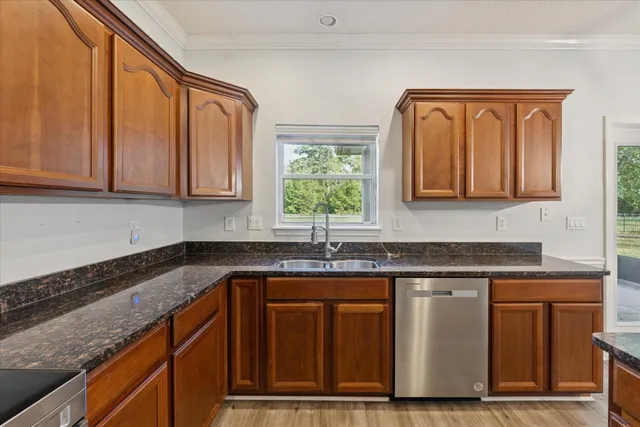a kitchen with granite countertop a sink stainless steel appliances and cabinets