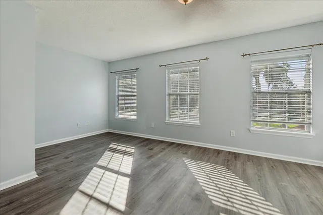 an empty room with wooden floor and windows