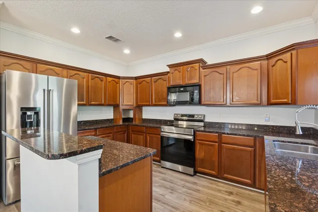a kitchen with stainless steel appliances granite countertop a refrigerator a stove top oven a sink and dishwasher