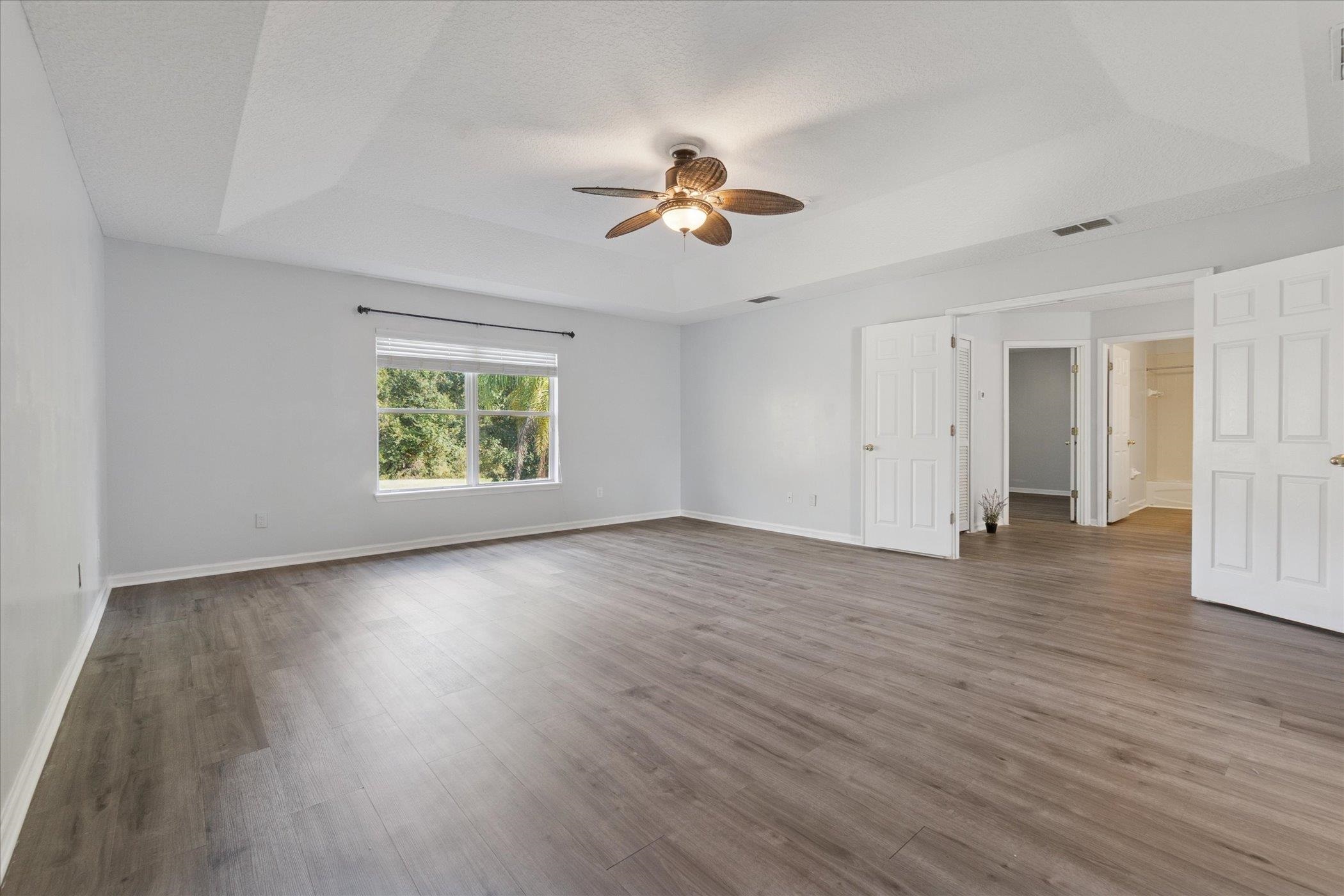 140 Corral Circle St. Augustine, FL 32092 - Photo 9 of 46 an empty room with wooden floor ceiling fan and windows