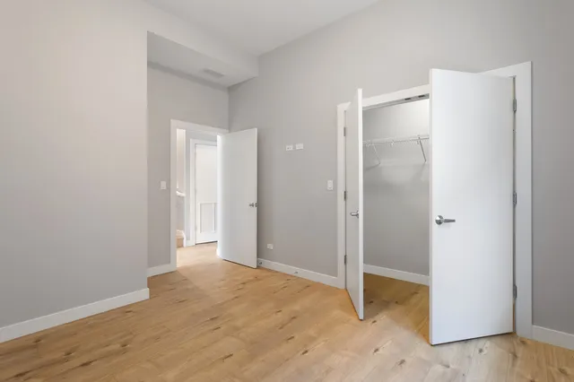 a view of an empty room with wooden floor and a bathroom