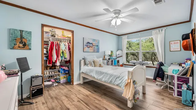 a bedroom with a bed a computer on desk and a dresser next to a window