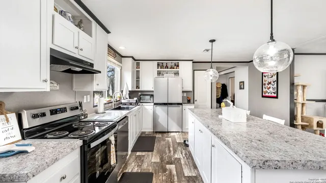 a kitchen with granite countertop a stove a sink a refrigerator and a wooden floors