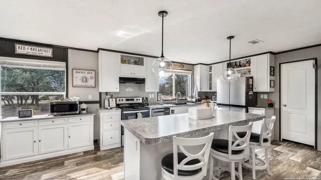 a kitchen with stainless steel appliances kitchen island granite countertop a sink a stove and refrigerator