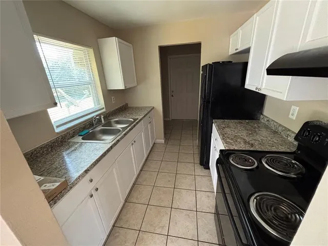 a kitchen with granite countertop a stove sink and refrigerator