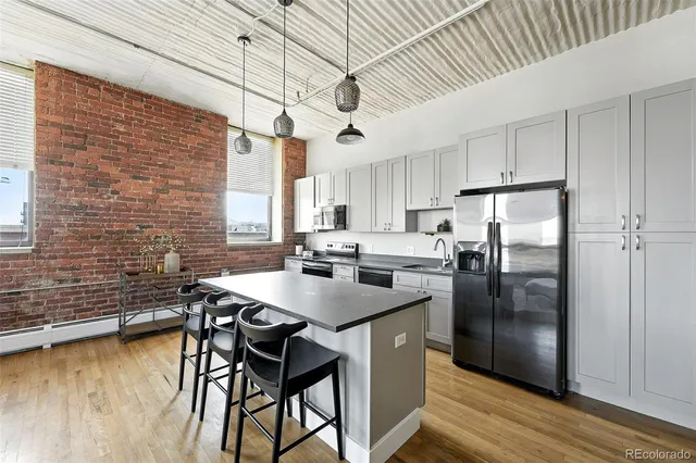 a kitchen with stainless steel appliances granite countertop a kitchen island hardwood floor sink stove dining table and chairs