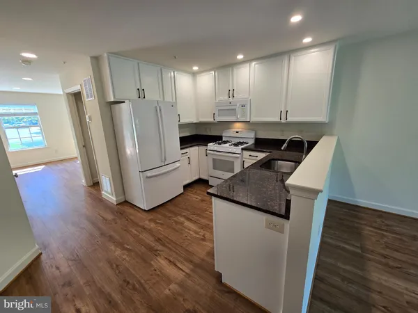 a kitchen with a sink stainless steel appliances and wooden floor