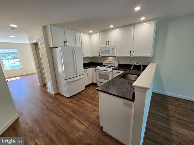 a kitchen with a sink stainless steel appliances and wooden floor
