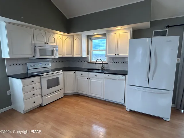 a kitchen with white cabinets and white appliances