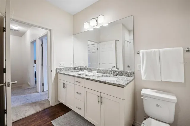 a bathroom with a granite countertop sink a toilet and a mirror