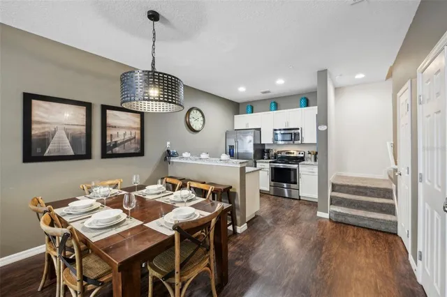 a open dining room with stainless steel appliances wooden floor dining table and chairs