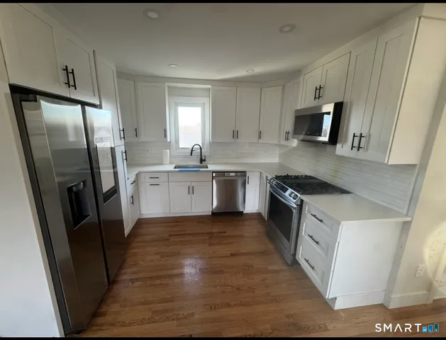 a kitchen with stainless steel appliances a refrigerator a sink a stove top oven and cabinets