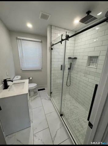 a bathroom with a granite countertop sink a toilet and shower
