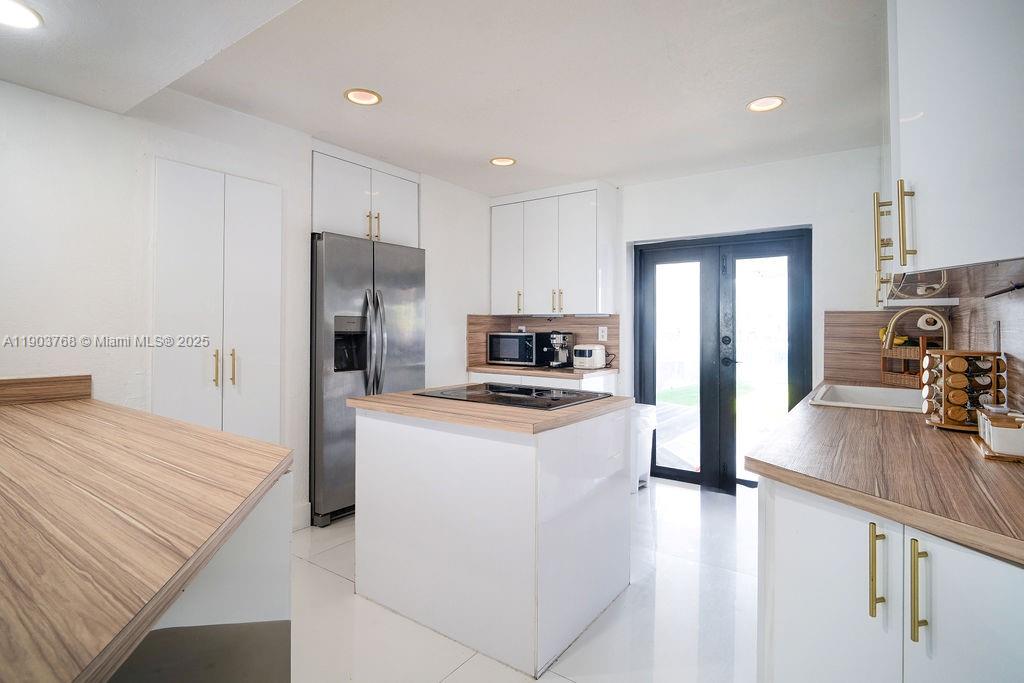 1960 Southwest 128th Court Miami, FL 33175 - Photo 15 of 32 a kitchen with kitchen island a stove a refrigerator a sink a stove and white cabinets with wooden floor