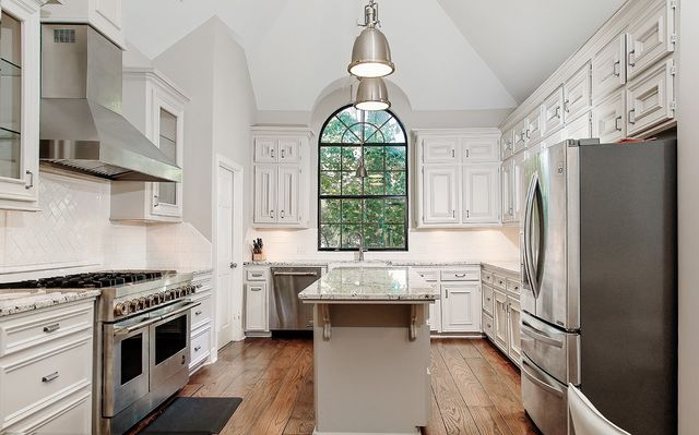 a kitchen with stainless steel appliances granite countertop a stove a refrigerator and a white cabinets