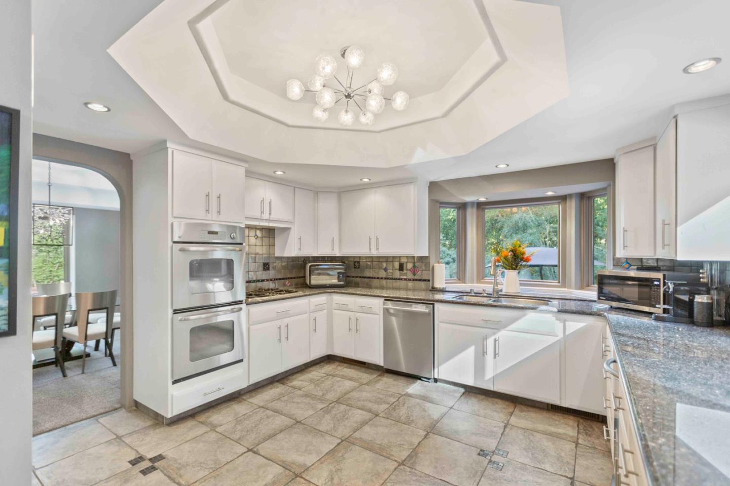 23491 Summit Road Los Gatos, CA 95033 - Photo 16 of 77 a kitchen with stainless steel appliances granite countertop a stove top oven a sink dishwasher a dining table and chairs with white cabinets