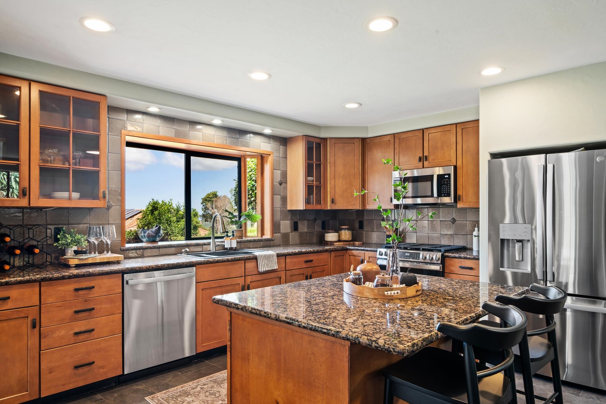 84 Mano Drive Kula, HI 96790 - Photo 12 of 25 a kitchen with stainless steel appliances granite countertop a stove top oven a sink dishwasher a dining table and chairs with wooden floor