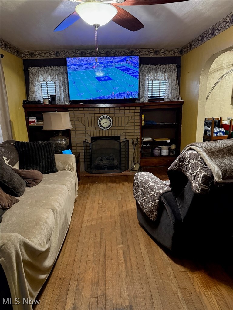 1311 Warner Road Southeast Canton, OH 44707 - Photo 2 of 14 Living room featuring wood-type flooring, a fireplace, arched walkways, and a ceiling fan
