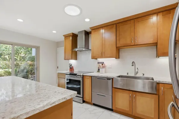 a kitchen with stainless steel appliances granite countertop a refrigerator a stove and a sink