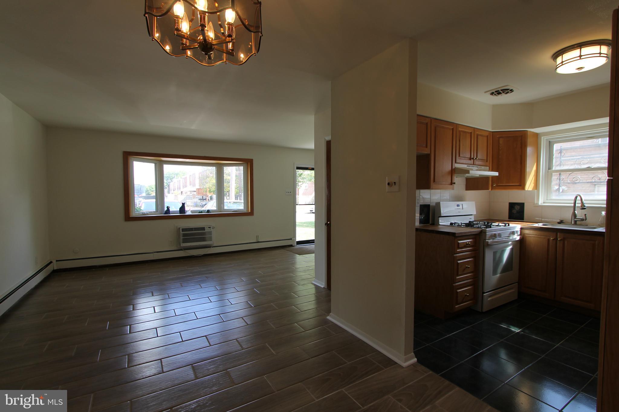 8244 Woolston Avenue Philadelphia, PA 19150 - Photo 8 of 19 a kitchen with stainless steel appliances granite countertop a refrigerator stove top oven and cabinets with wooden floor