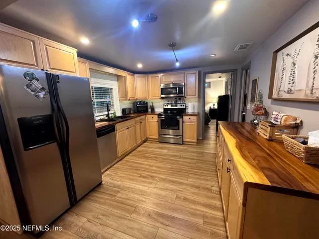 a kitchen with stainless steel appliances a refrigerator a sink a stove a oven a dining table and chairs