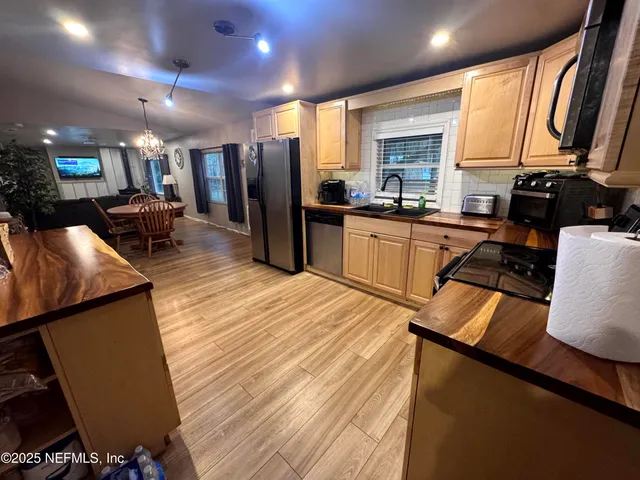 a kitchen with stainless steel appliances granite countertop a refrigerator stove top oven dining table and chairs