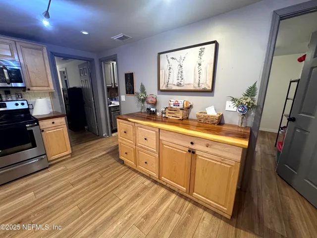 a kitchen with stainless steel appliances a refrigerator sink and wooden floor
