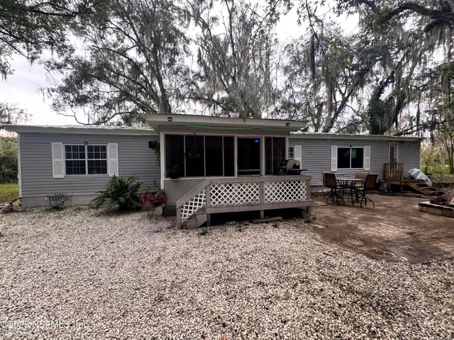 a view of a house with a yard and large trees