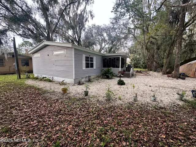 a backyard of a house with large trees and fence