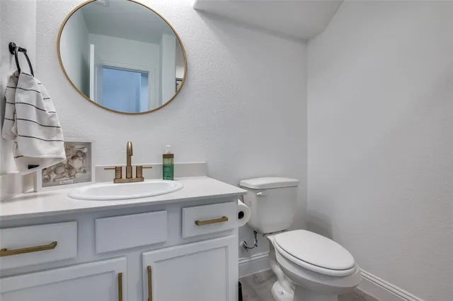a bathroom with a granite countertop toilet a sink and mirror