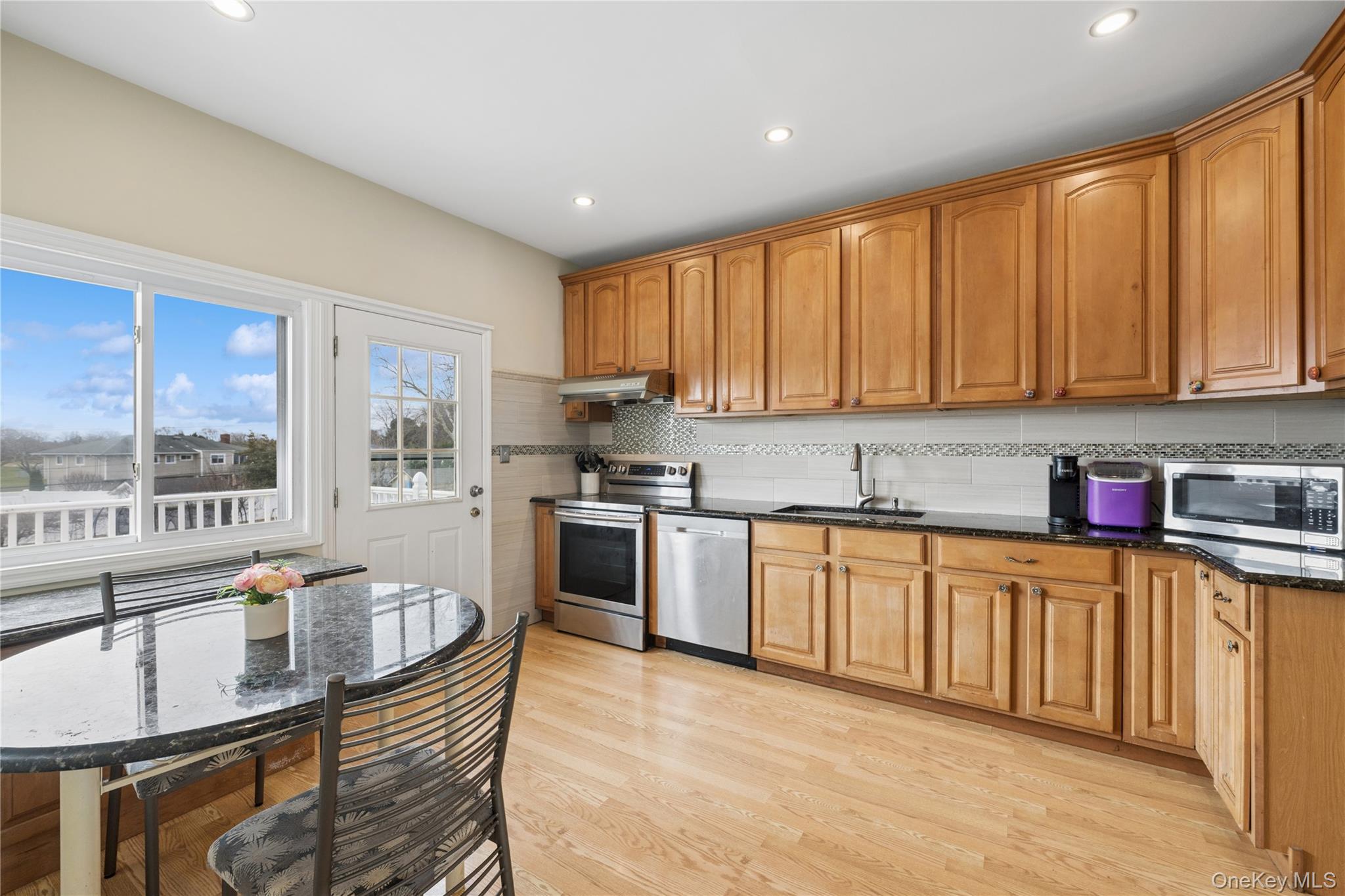 40 Scholar Lane Commack, NY 11725 - Photo 13 of 49 a kitchen with stainless steel appliances granite countertop a stove top oven a sink dishwasher a dining table and chairs with wooden floor