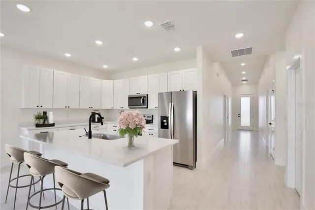 a kitchen with stainless steel appliances a refrigerator sink and white cabinets