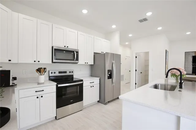 a kitchen with stainless steel appliances a refrigerator sink and white cabinets