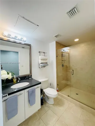 a bathroom with a granite countertop sink a toilet a mirror and shower