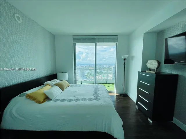 a bedroom with a bed and a flat tv screen on the dresser