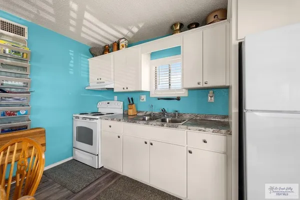 a kitchen with granite countertop a sink a stove and cabinets