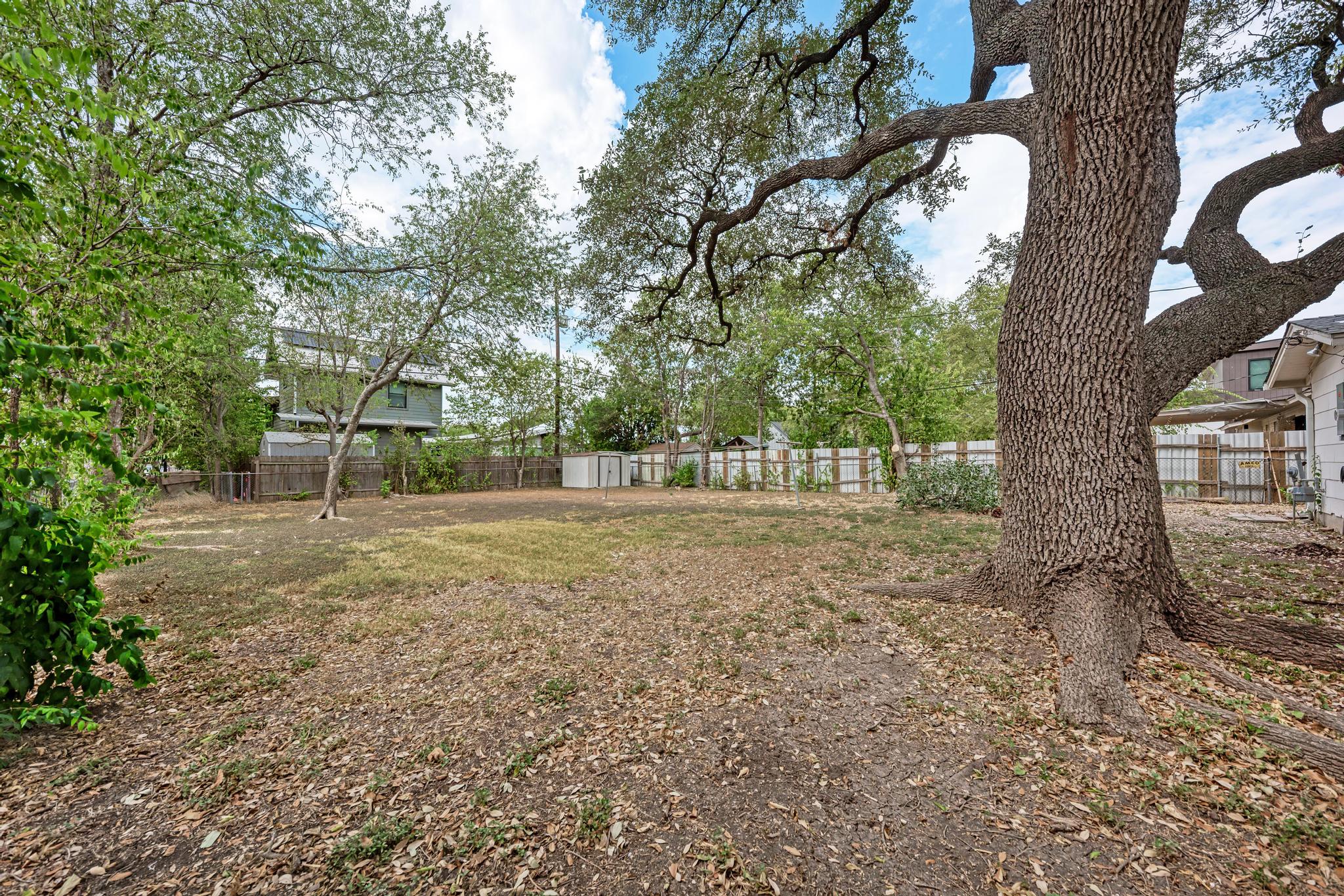7804 Rutgers Avenue Austin, TX 78757 - Photo 24 of 32 Mature shade trees frame a spacious lawn enclosed by perimeter fencing.
