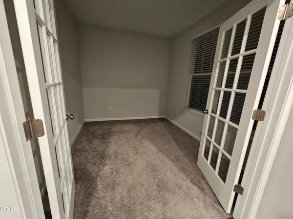 a view of an empty room with wooden floor and door