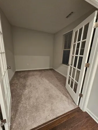 a view of an empty room with wooden floor and stairs
