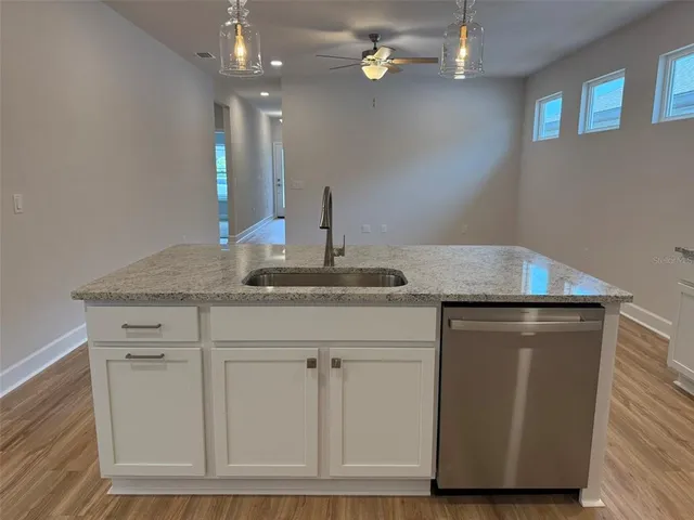a kitchen with granite countertop a sink cabinets and wooden floor