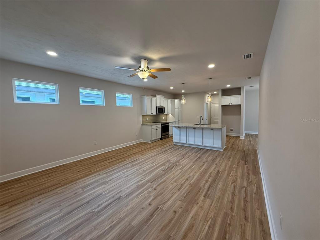9654 Southwest 67th Lane Gainesville, FL 32608 - Photo 5 of 44 an empty room with wooden floor kitchen view and a window