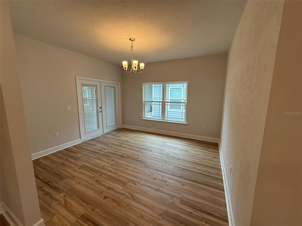 9654 Southwest 67th Lane Gainesville, FL 32608 - Photo 7 of 44 an empty room with wooden floor chandelier and windows