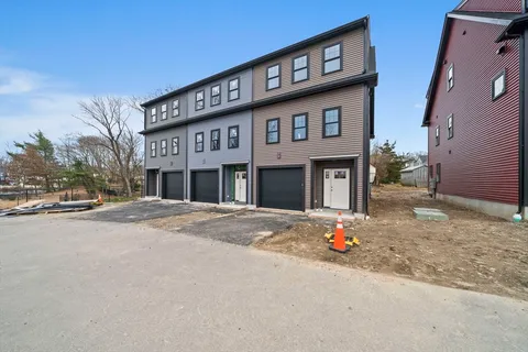 a front view of a building with lot of cars and trees