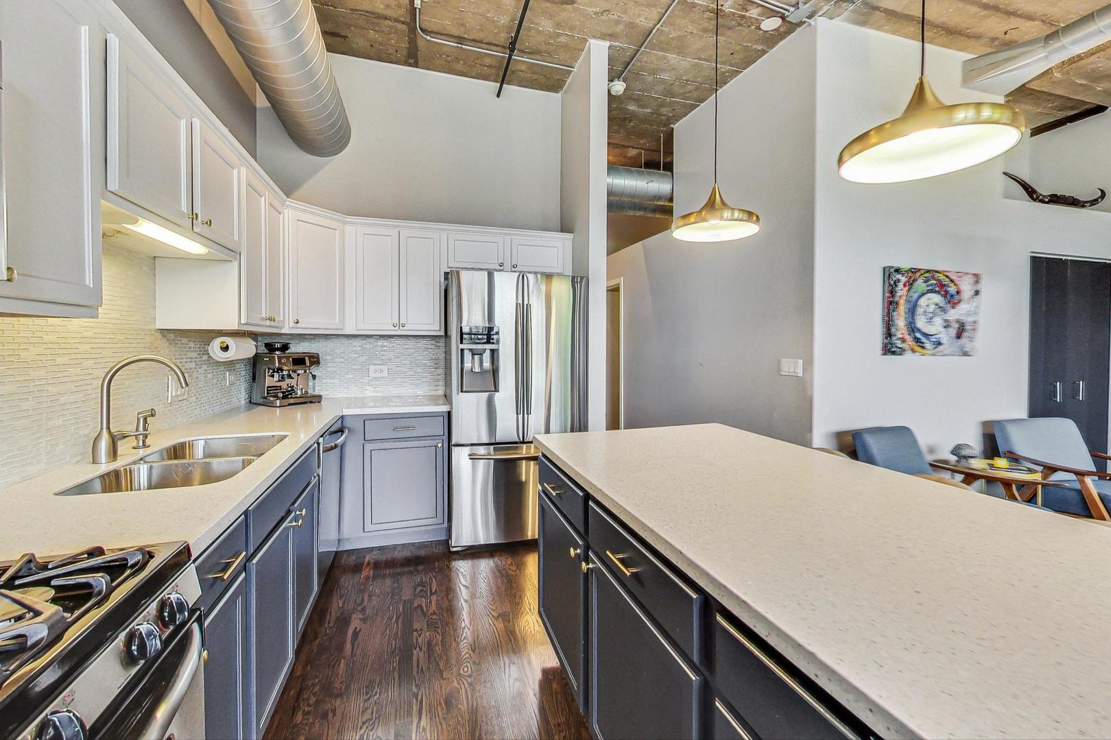 1111 West 14th Place, Unit 328 Chicago, IL 60608 - Photo 22 of 49 a kitchen with kitchen island a sink appliances and cabinets