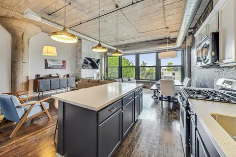 a kitchen with stainless steel appliances granite countertop a stove a sink dishwasher and chairs with wooden floor