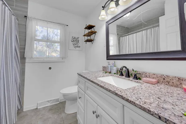 a bathroom with a granite countertop sink a toilet and a window